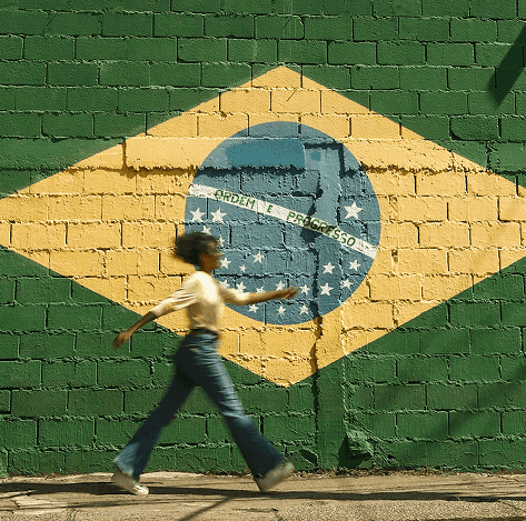 Woman walking past a wall painted with the Brazilian flag