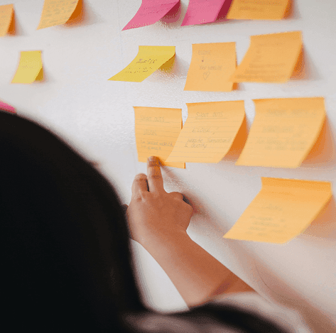 Person arranging sticky notes on a wall during a service design session