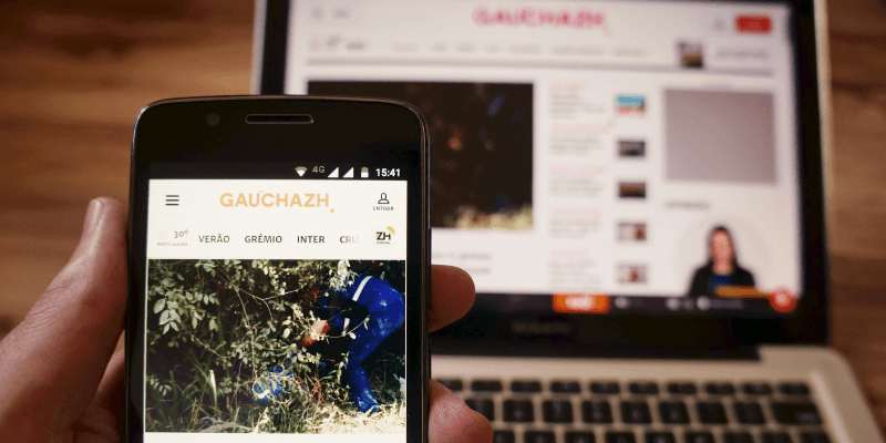 Um celular em primeiro plano mostrando o site da GaúchaZh e em segundo plano um computador apresentando o mesmo site na versão desktop, representando o trabalho realizado pela Uzzer.