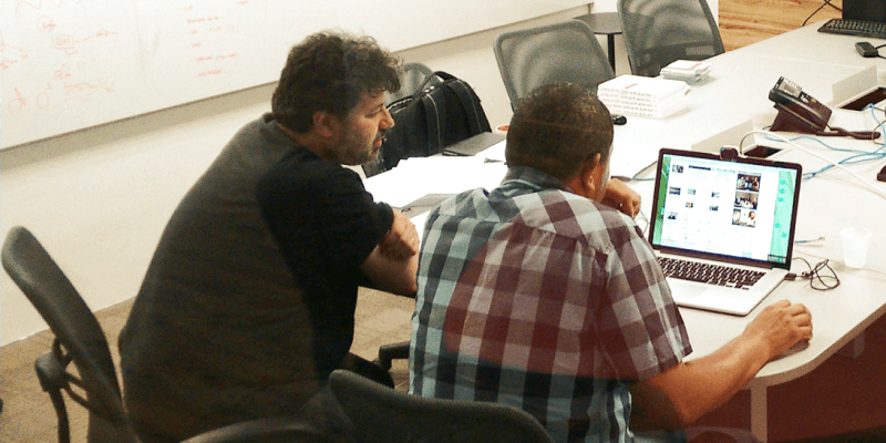 Consultor da Uzzer, Marcelo Morais, está sentado ao lado de uma pessoa que está realizando um teste de usabilidade do protótipo de GauchaZh em um computador.