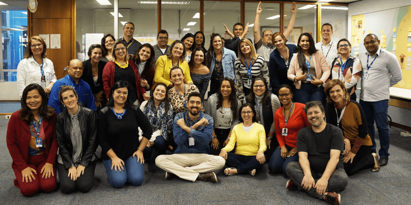 Cerca de 30 pessoas algumas sentadas e outras de pé em posição para foto final da primeira turma do curso de Cultura UX para o Sebrae Nacional.