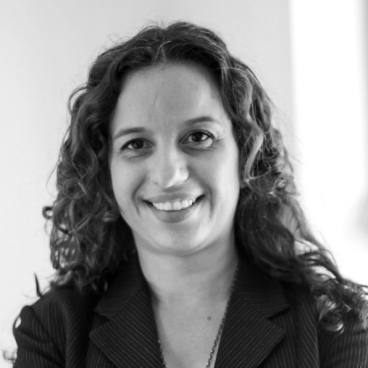 Lisandra Maioli em foto preto e branco de cabelos cacheados e sorrindo.